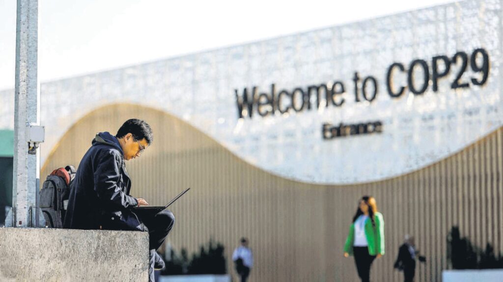 A man uses his laptop as he sits near the COP29 Un 1732299765692