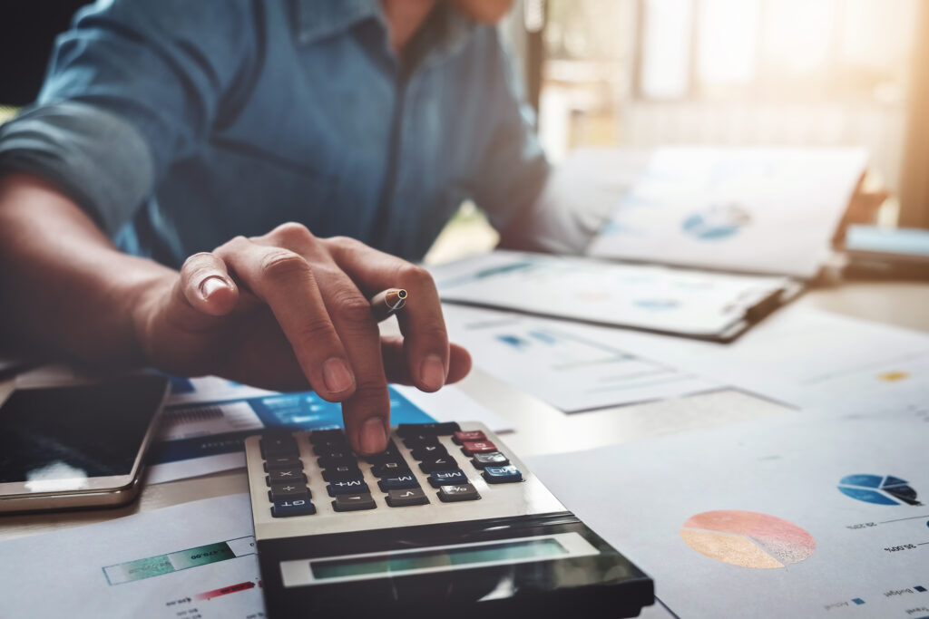 person with calcualtor examining financial data