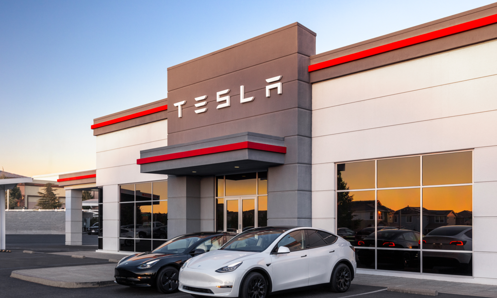 a tesla dealership with two tesla electric vehicles parked out front